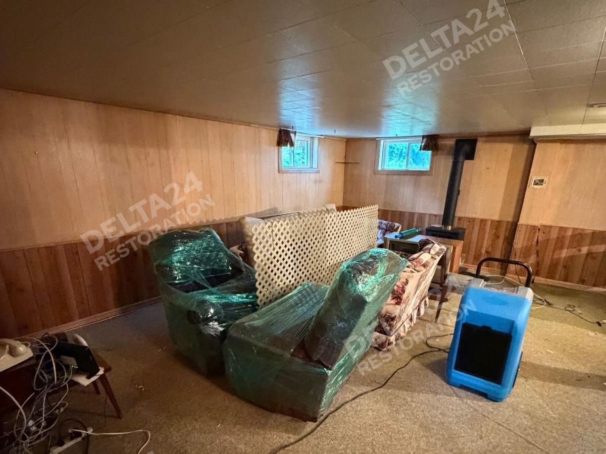 Before: soaked carpet, with the furniture wrapped and a dehumidifier already running
